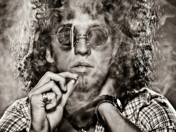 Ein Mann, Hippie, zieht an einem Joint. 