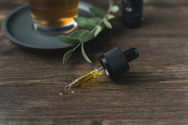 Eine Pipette mit einem gelblichem Öl ist zu sehen, wahrscheinlich handelt es sich um das gesundheitsfördernde CBD- Öl.