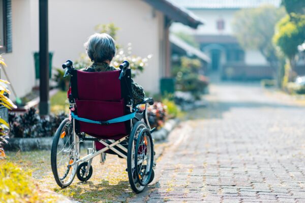 Eine alte Frau im Rollstuhl ist von hinten zu sehen. Hoffentlich bleibt sie von Alzheimer befreit.