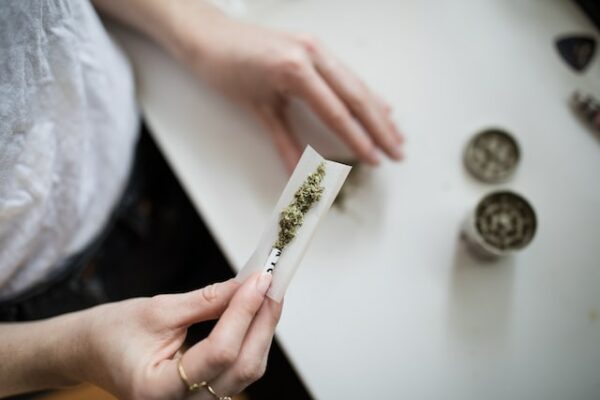 Eine Frau hält ein Pape mit Tabak und Gras in der Hand. Sie baut sich einen Joint.