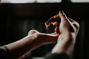 Es sind zwei Hände zu sehen, die rechte Hand tropft aus einem Fläschen Öl in die andere Hand. Bestimmt CBD Öl.