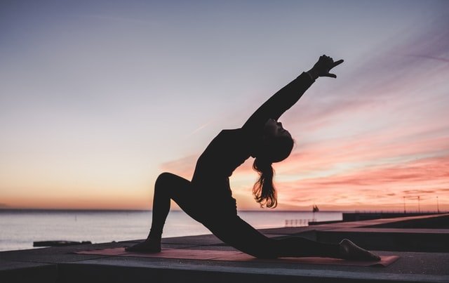 CBD und Yoga können auch dieser Yoga Praktizierenden helfen. Eine Frau macht eine Yoga Übung vor einem rotem Himmel.