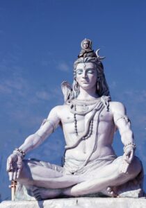 shiva- gott des hanfs, ist hier zu sehen als Steinstatue vor einem blauen Himmel. Er hat CBD und Yoga auch kombiniert.
