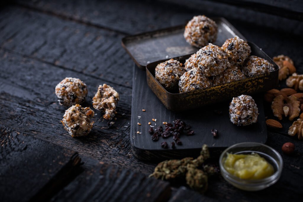 Energy Balls von Mary Mellow hier sind Energy Balls zu sehen, die in einer Box liegen. Darum herum liegen die verschiedenen Zutaten, die in den Balls sind, wie Nüsse.