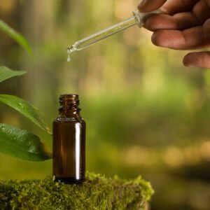 Eine Braunglasflasche mit Tropfeneinsatz ist zu sehen, die vermutlich in einem Wald steht. . Foto: Canva 