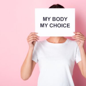 Frau mit einem weißen T-Shirt vor einem rosa Hintergrund hat ein Schild in der Hand auf dem steht: my Body, my Choice