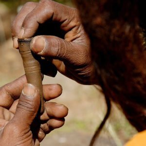die Hände eines Mannes mit dunkler Haut ist zu sehen, der eine Chillum Pfeife stopft.