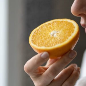 Eine Frau riecht an einer Orange.