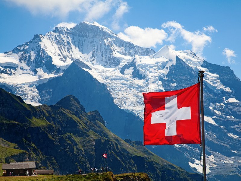 Cannabis in der Schweiz. Die schweizer Flagge vor den wunderschönen Alpen