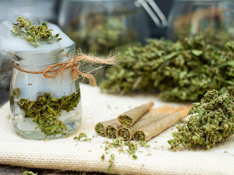Cannabisblüten in Joint und in einem Glas sind zu sehen.