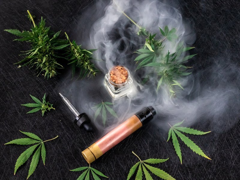 Cannabisblätter mit Extrakt, Feuer und einem Joint