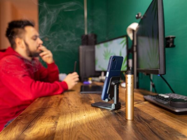 Kiffen am Arbeitsplatz, ist das mit der Legalisierung erlaubt? Ein Mann sitzt am PC und raucht einen Joint.