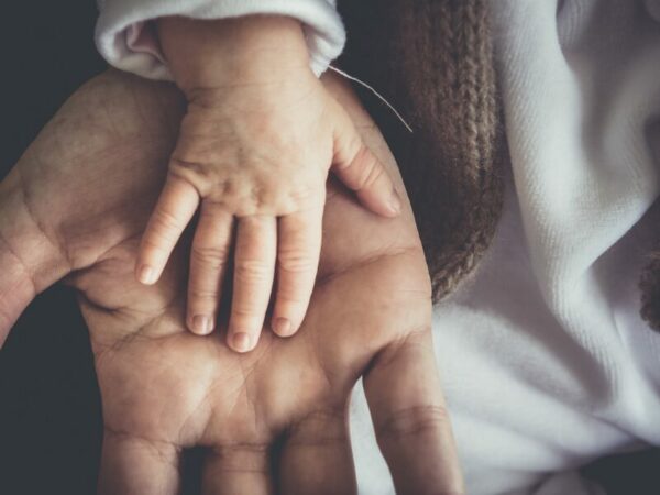 Eine Erwachsene Hand hält eine Kinderhand