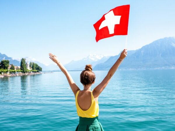 Eine Frau hält die Schweizer Flagge hoch. In der Schweiz werden bereits verschiedene Modelle zur Cannabisabgabe getestet.