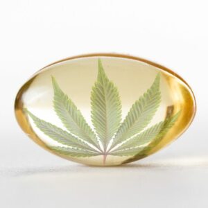 CBD effektiv nutzen. Hier ist eine Kapsel mit einem Hanfblatt zu sehen.