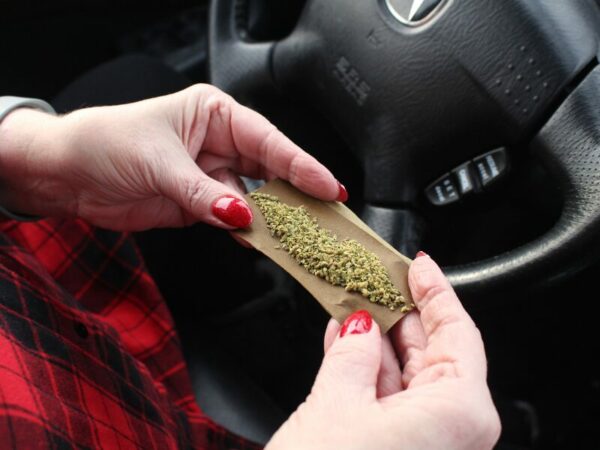Cannabis und Verkehrssicherheit, passt das zusammen? Eine Frau dreht hier einen Joint im Auto