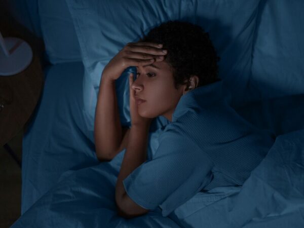 eine Frau liegt traurig im Bett. Evtl. leidet sie an einer Psychose. 