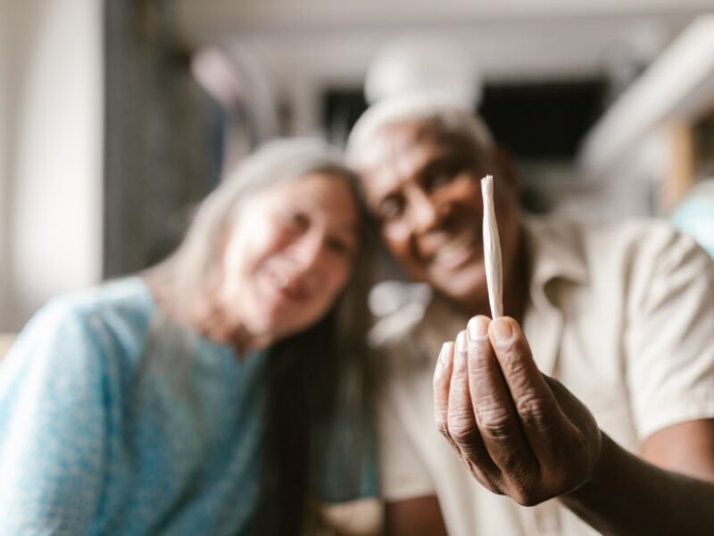 eine ältere Dame und ein älterer Herr halten einen Joint in der Hand. Cannabis im Alter kann auch Heilung bringen.