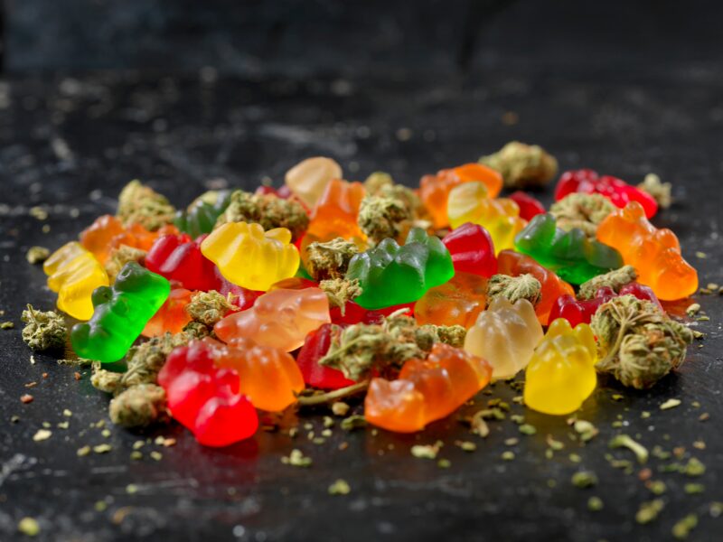 THC Gummibärchen Rezept. Hier sind bunte Gummibärchen mit Cannabisblüten zu sehen.