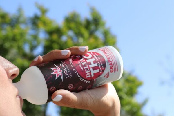 Eine Frau trinkt aus einer Flasche mit THC Etikett.