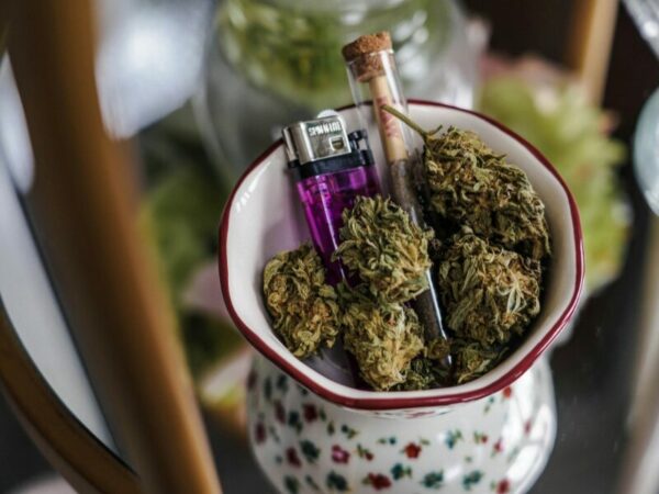 eine Tasse mit Cannabisblüten, einem Joint und einem Feuerzeug 