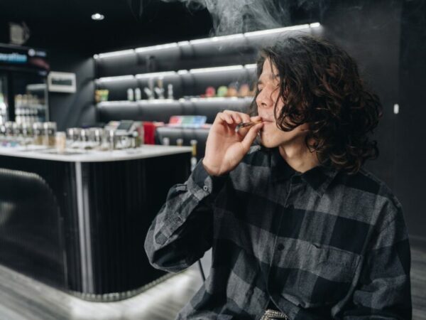 Ein junger Mann zieht an einem Joitn in einer Bar. Aufklärung ist sehr wichtig in Bezug auf Drogen und der Nutzung von Cannabis. 